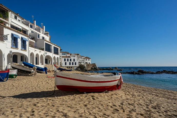 a red and white boat sitting on top of a sandy beach